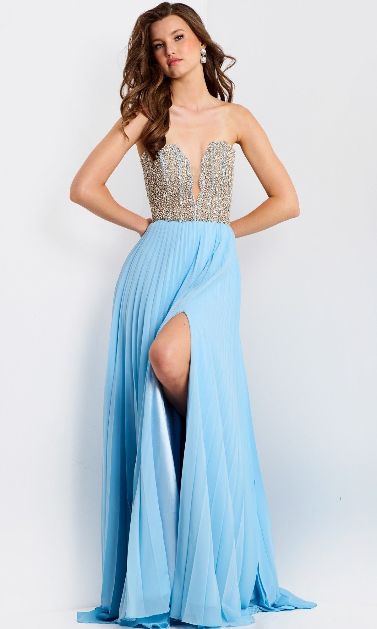 A woman wears the Jovani 44358 long prom dress, featuring a strapless beaded bodice and a light blue pleated chiffon A-line skirt with a high slit.